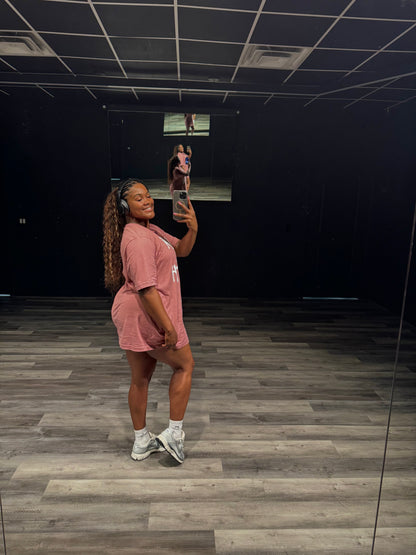 Person taking a mirror selfie in a room with dark walls and wooden floor.